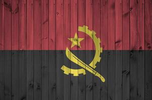 angola drapeau représenté dans brillant peindre couleurs sur vieux en bois mur. texturé bannière sur rugueux Contexte photo