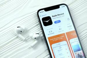 Kharkov, Ukraine - Mars 5, 2021 radio record icône et application de app boutique sur iphone 12 pro afficher écran avec airpods pro sur blanc table photo