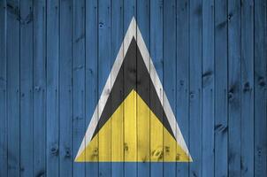 Saint lucia drapeau représenté dans brillant peindre couleurs sur vieux en bois mur. texturé bannière sur rugueux Contexte photo