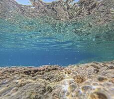 sous-marin image de une rocheux littoral avec turquoise l'eau vers le surface photo