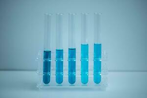 5 bleu tester tubes mis dans une médical tube grille avec une blanc arrière-plan, médical concept. photo