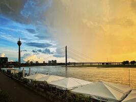 Düsseldorf, Allemagne - septembre 12 2023 - le réglage Soleil des peintures une pluie nuage dans le soir heures près le Rhin rivière dans Düsseldorf, Allemagne. photo