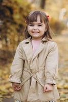 belle petite fille dans un manteau beige se promène dans le parc en automne