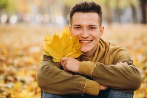 garçon avec un bouquet de feuilles souriant et rêvant dans le parc en automne photo