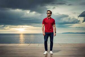 une homme dans des lunettes de soleil et une rouge chemise permanent sur une Dock à la recherche en dehors à mer. généré par ai photo