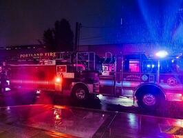 Portland, Oregon, Etats-Unis - 11.02.2023 Feu un camion avec clignotant lumières à nuit, appelé à une Feu alarme dans le ville de dalle zone. pluie. photo