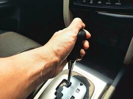 homme la gauche main en portant le voiture équipement levier. voiture centre console avec automatique changement de vitesse levier. photo