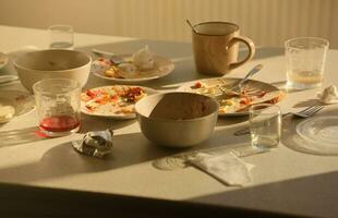 vider les assiettes sales avec des cuillères et des fourchettes sur la table après le repas. concept de fin de banquet. vaisselle non lavée photo