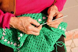 un vieux femme est tricot une vert crocheté sac photo