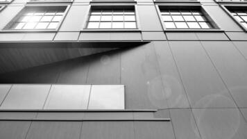 une vue à une tout droit façade de une moderne bâtiment avec une foncé gris façade. foncé gris métallique panneau façade. moderne architectural détails. noir et blanche. photo