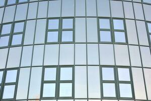 moderne Bureau bâtiment avec verre façade sur une clair ciel Contexte. transparent verre mur de Bureau bâtiment. photo