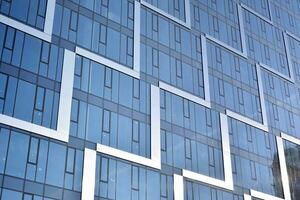 verre bâtiment avec transparent façade de le bâtiment et bleu ciel. de construction verre mur reflétant bleu ciel. abstrait moderne architecture fragment. contemporain architectural Contexte. photo