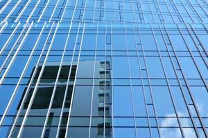 verre bâtiment avec transparent façade de le bâtiment et bleu ciel. de construction verre mur reflétant bleu ciel. abstrait moderne architecture fragment. contemporain architectural Contexte. photo