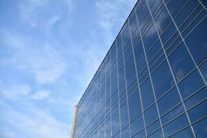 verre bâtiment avec transparent façade de le bâtiment et bleu ciel. de construction verre mur reflétant bleu ciel. abstrait moderne architecture fragment. contemporain architectural Contexte. photo