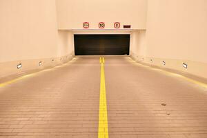 Départ de le souterrain garage avec blanc portail. intérieur piliers peint Jaune. photo