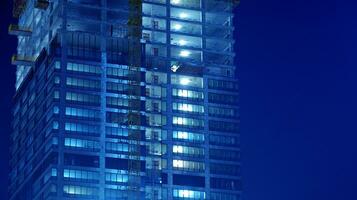 modèle de Bureau bâtiments les fenêtres illuminé à nuit. verre architecture , d'entreprise bâtiment à nuit - affaires concept. bleu graphique filtre. photo