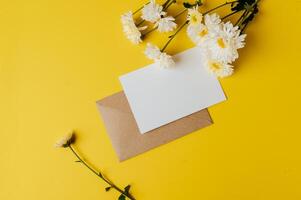 une carte vierge avec enveloppe et fleur est placée sur fond jaune photo