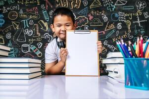 enfant assis et montrant une planche à pince dans la salle de classe photo