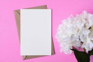 papier vierge avec des fleurs placées sur un fond rose photo