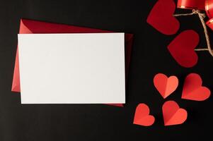 papier blanc et papier coeur rouge collés sur fond noir. photo