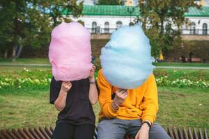 deux les enfants sont séance avec une grand coton bonbons bleu et lumière bleu. frère et sœur, marcher, enfance, bonbons photo