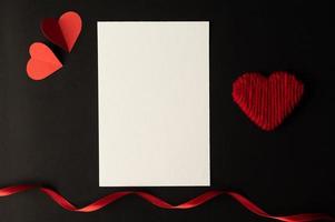 papier blanc et papier coeur rouge collés sur fond noir. photo