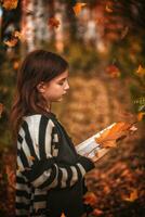 fille avec taches de rousseur avec une livre parmi l'automne feuilles photo