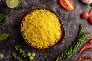 riz au curcuma dans une tasse brune aux épices sur ciment noir. photo