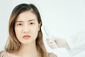 peau problème et beauté de asiatique fille. dermatologue utilisation grossissant verre Regardez qui démange peau de peau allergique, stéroïde allergie, sensible peau, chimique allergie, éruption cutanée, insecte morsures, dermatite. photo