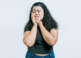 Jeune femme Souffrance avec mal aux dents isolé. fille frottement joue avec mal aux dents sur blanc Contexte. photo