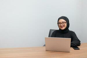 portrait de attrayant asiatique hijab femme travail sur sa portable. musulman fille Faire tâche dans bureau. employé et free-lance ouvrier concept. photo