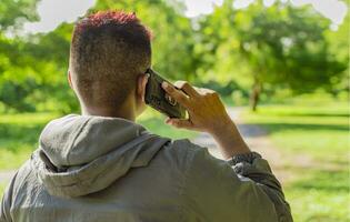 proche en haut de une homme appel sur le téléphone, proche en haut de une Jeune homme appel sur le téléphone dans le champ, homme de retour appel sur cellule téléphone photo