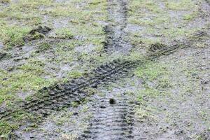 roue Piste sur boue. traces de une tracteur ou lourd hors route voiture sur marron boue dans humide Prairie photo