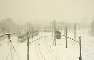 un long train de voitures voyageurs se déplace le long de la voie ferrée. paysage ferroviaire en hiver après les chutes de neige photo