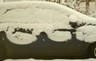 fragment de la voiture sous une couche de neige après une forte chute de neige. le corps de la voiture est recouvert de neige blanche photo