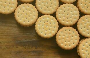 un biscuit sandwich rond fourré à la noix de coco se trouve en grande quantité sur une surface en bois marron. photo de friandises comestibles sur un fond en bois avec espace de copie