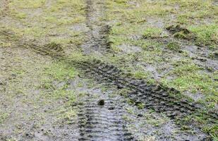 roue Piste sur boue. traces de une tracteur ou lourd hors route voiture sur marron boue dans humide Prairie photo