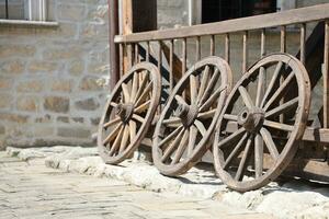 Trois vieux en bois roues pour cheval chariots penché contre une en bois mur photo