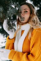 adolescent blond dans une Jaune chandail à l'extérieur dans l'hiver. une adolescent fille sur une marcher dans hiver vêtements dans une neigeux forêt photo