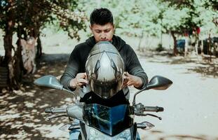 homme sur moto en mettant sur casque. motocycliste en mettant sur sécurité casque, motard moto sécurité concept. Jeune motocycliste homme en mettant sur sécurité casque photo