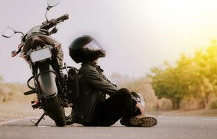 motocycliste séance suivant à le sien moto sur le route. motocycliste séance et penché sur le sien moto sur le asphalte photo