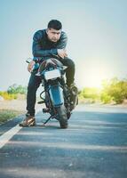 Beau motocycliste dans veste séance sur le sien moto à le côté de le route. portrait de Beau motard sur le sien moto à la recherche à caméra en plein air photo