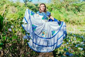 nicaraguayen femme dans traditionnel populaire costume dans une champ de les myflores, souriant femme dans nationale populaire costume dans une champ entouré par fleurs. gens dans nicaraguayen nationale populaire costume photo