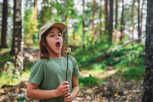 marrant mignonne fille soufflant sur chaud guimauves rôti sur une Feu photo