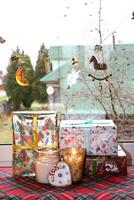 Noël fenêtre avec guirlande, cadeaux, bougies dans verre dans chandeliers, pain d'épice dans une pays loger, verticale photo