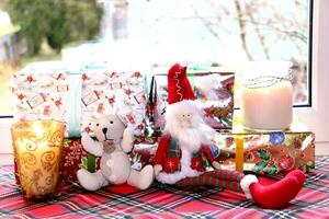 Noël cadeaux et bougies avec jouet gnome et nounours ours près le fenêtre, horizontal photo, fermer photo