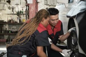 professionnel Masculin automobile superviseur qualifié noir femelle mécanicien technicien à vis voiture roue des noisettes pour réparation à garage, véhicule entretien un service travaux industrie Occupation affaires emplois. photo