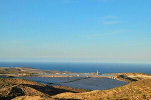 solaire panneaux sur le côté de une colline surplombant le océan photo