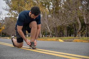 homme sportif attachant ses lacets tout en exerçant à l'extérieur photo