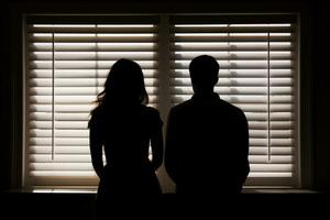 silhouette de une couple orienté vers une fenêtre avec stores. ai généré photo